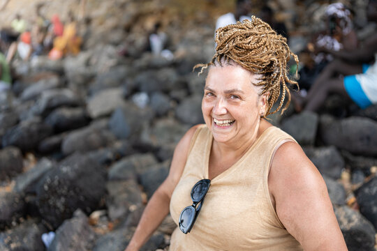 woman with braids on the beach laughing 