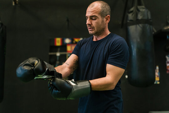 Focused man putting on boxing gloves in gym