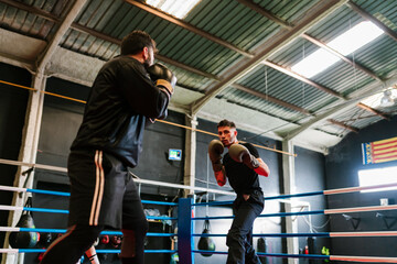 Men boxing on ring in gym