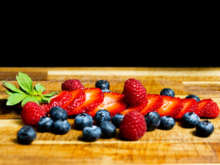 Sliced Strawberry with berries on a wooden table