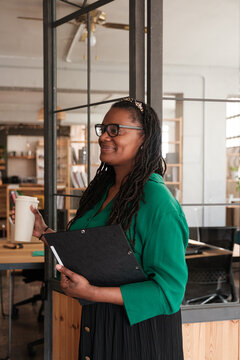 Entrepreneur standing and looking documents at workplace