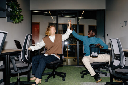 Multiracial colleagues giving high five during play
