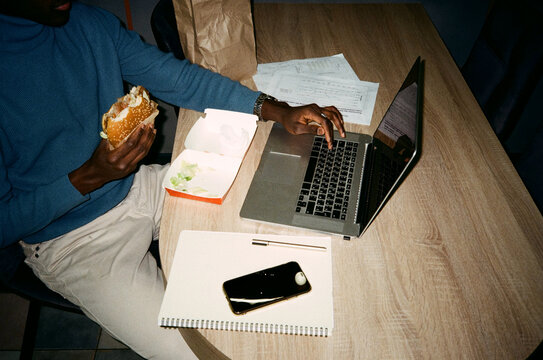 Anonymous worker with burger during work