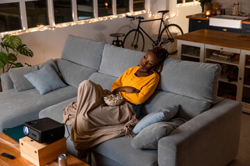 black woman watching a movie with a projector in her apartment
