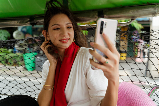A woman uses a smartphone during a ride on a tuk-tuk in Bangkok