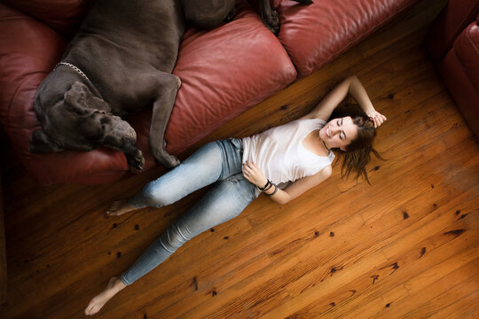 Woman lying on living room floor playing with big dog