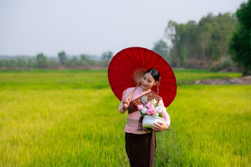 Pretty Asian women in traditional Thai dress. Beautiful traditional Thai dresses by Asian Buddhists make merit at the Temple a tourist attraction, a