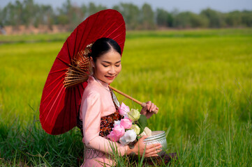 Pretty Asian women in traditional Thai dress. Beautiful traditional Thai dresses by Asian Buddhists make merit at the Temple a tourist attraction, a