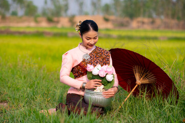 Pretty Asian women in traditional Thai dress. Beautiful traditional Thai dresses by Asian Buddhists make merit at the Temple a tourist attraction, a