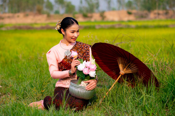 Pretty Asian women in traditional Thai dress. Beautiful traditional Thai dresses by Asian Buddhists make merit at the Temple a tourist attraction, a