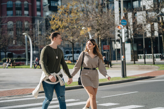 Happy loving couple holding hands and crossing road