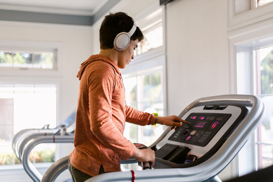 Teenage boy setting interface up on treadmill at gym
