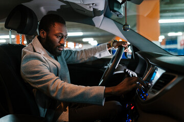 Focused black male driver using dashboard in car