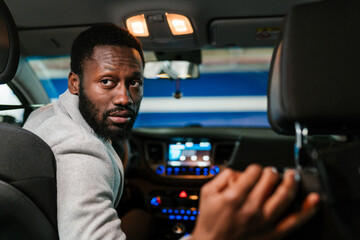 Serious black man driving car