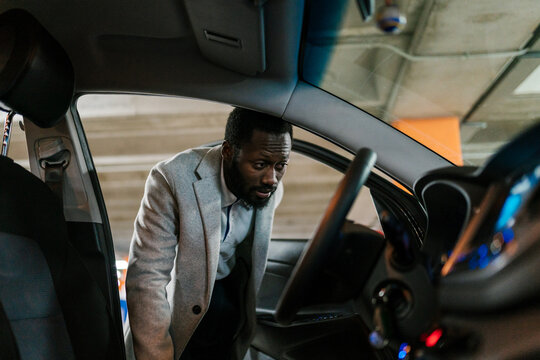 Black driver checking car dashboard