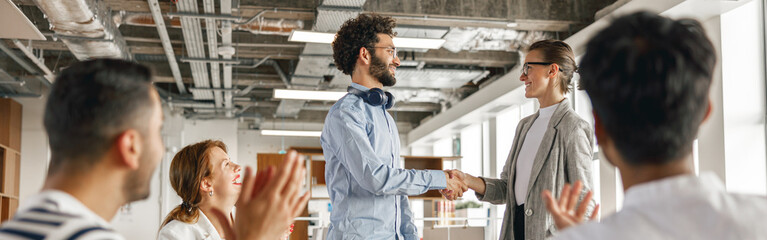 Smiling female boss leader shaking hand of new team member recruiting him for job on staff briefin