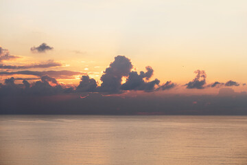 golden sea water surface and dramatic cloudy orange sky at sunset