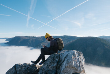 Male Hiker Sitting on Mountain Top While Using Smartphone 
