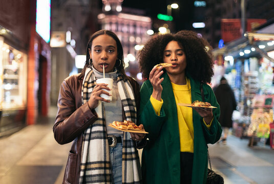 Young black women eating fast food on the street at night