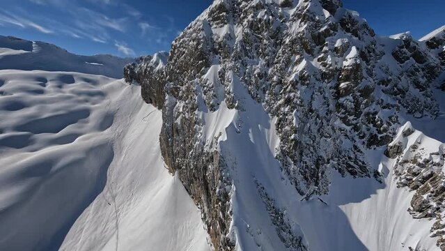 Sunny winter day mountain valley panorama flying over cliff stone ridge texture snow sunny landscape aerial view. FPV sport drone shot beautiful wild frozen nature environment rock with hole scenery