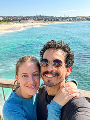 Naklejka premium Couple hugging and taking a selfie in front of a beach