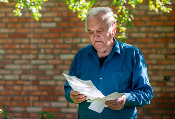senior grey-haired man check bills