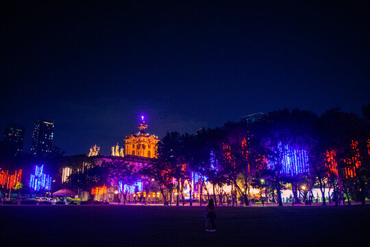 People hugging under Christmas lights in the city streets. University of Santo Tomas, Manila, Philippines