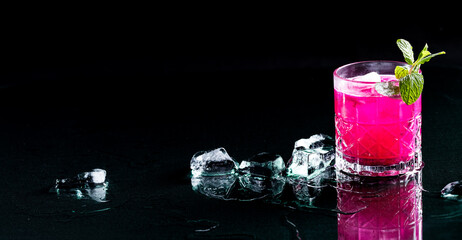 A bright pink dragonfruit cocktail with ice, against a black background.