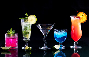 A row of bright colourful cocktails on a glass table, against black. - Powered by Adobe