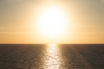 brown sea water surface and big bright sun in the yellow sky