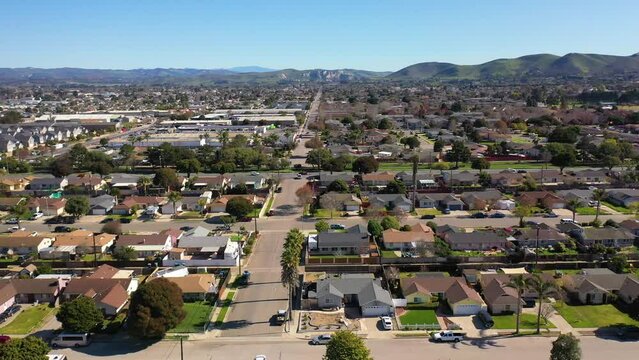2023 - Excellent aerial footage of cars driving through a residential area by the mountains in Lompoc, California.