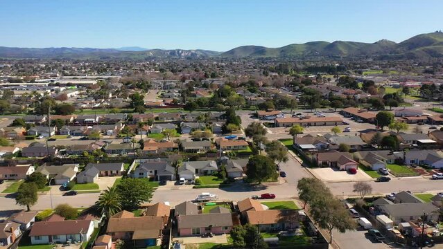 2023 - Excellent aerial footage of cars driving through a residential area by the mountains in Lompoc, California.