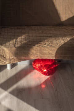 a balloon in the shape of a heart at home under the sofa