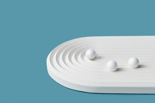 White cement ribbed ellipse with small spheres.