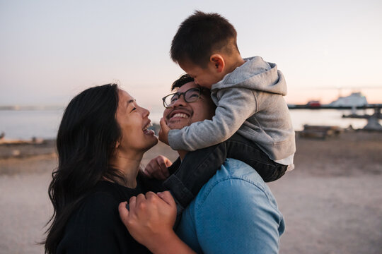 Family of three enjoying shoulder ride time together outside at 