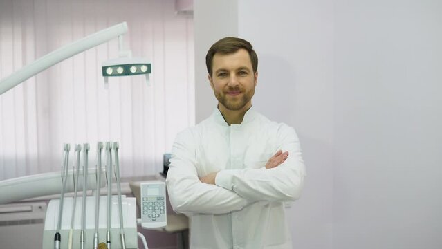 Young male dentist in clinic. Attractive male dentist in doctors white lab coat posing in modern dental office