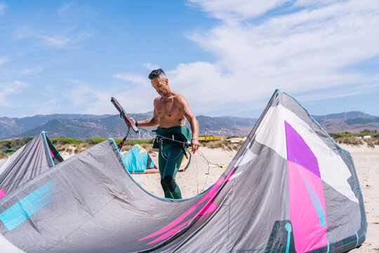 Man with equipment for kitesurfing on beach