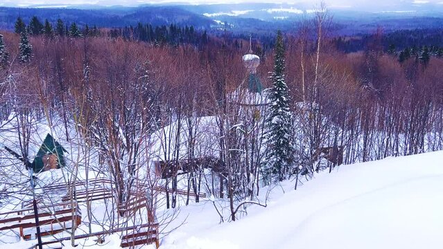 View of the chapel near the Belogorsky St. Nicholas Orthodox Missionary Monastery. Winter forest. The temple on the hill in winter. Russia, Perm Krai, Belaya Gora. 4K