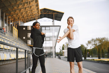 African-american woman and caucasian man training at the stadium