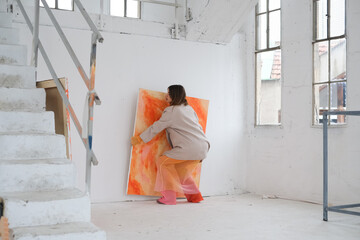 Female Artist Hanging Her Painting on Wall 