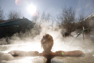 Anonymous female resting in outdoor pool with hot water