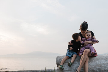 Fototapeta premium Mom and kids enjoying cuddles at the beach.