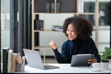 American African Woman working in the office with computer phone and Tablet.