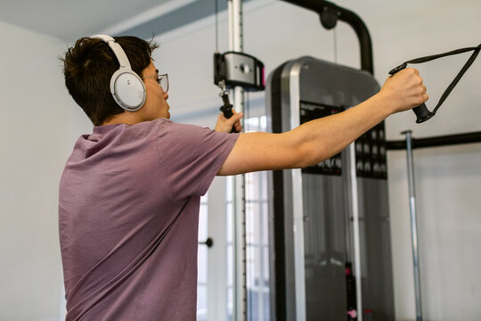 Teen boy using pulley gym machine exercising