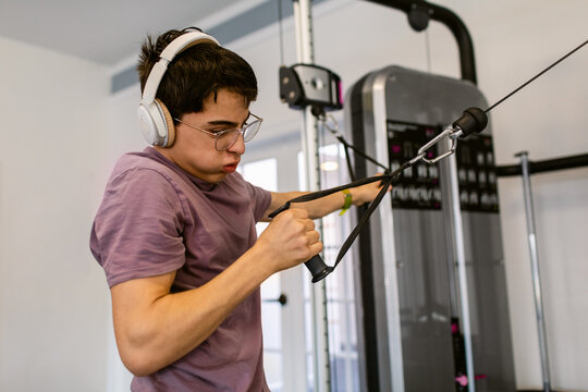 Teenage boy exercising arms in private gym 