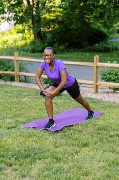 Smiling black teenage girl stretching outdoors during workout 