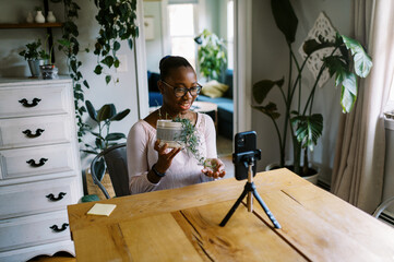 Smiling black girl vlogging about plants in her home