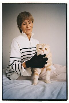 Woman sits on a couch with scottish fold cat