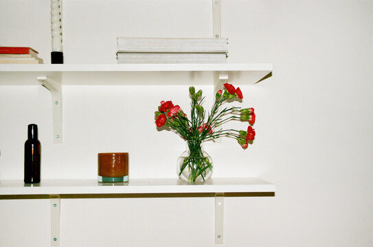 Film photo bouquet in a vase and stylish decor elements on the shelf
