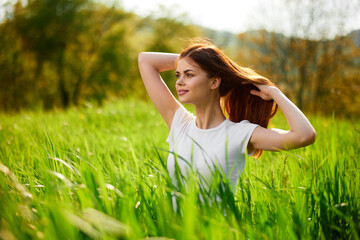 Naklejka na ściany i meble beautiful woman sitting in tall grass adjusting her hair